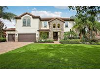 Charming two-story home with a stone entrance, lush landscaping, and a well-manicured lawn at 19711 Wellington Manor Blvd, Lutz, FL 33549