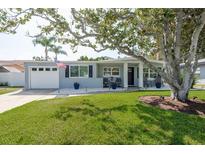 Charming single-story home with a well-manicured lawn, white rock landscaping, and inviting front porch seating at 2271 Carolyn Dr, Dunedin, FL 34698