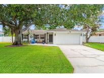 Charming single-story home with an attached garage, lush green lawn and mature shade tree at 2334 Tropical Shores Se Dr, St Petersburg, FL 33705