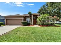 Charming single-story home with a well-manicured lawn, mature trees, and a welcoming front entrance at 2803 Abbey Grove Dr, Valrico, FL 33594
