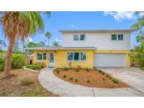 Charming two-story home featuring a well-manicured front yard, attached garage, and welcoming walkway at 320 Tallahassee Ne Dr, St Petersburg, FL 33702