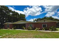 Charming single-story red brick home with a covered porch and beautiful landscaping at 3419 Pearson Rd, Valrico, FL 33596