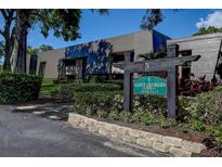 Attractive condo complex exterior with lush landscaping and a sign at 36750 Us 19 N # 24-213, Palm Harbor, FL 34684