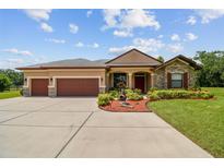 Inviting single-story home with a well-manicured lawn, mature landscaping, and a three-car garage at 4608 Scott Rd, Lutz, FL 33558