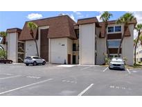 Exterior view of condo building with mature palms, convenient parking spaces, and neutral stucco facade at 6370 1St N St # 202, St Petersburg, FL 33702
