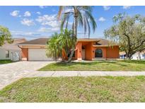 Charming single-story home with a well-manicured lawn, brick driveway and lush palm trees at 8601 Chadwick Dr, Tampa, FL 33635