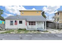 Charming single-story home with a covered front porch and American flags, ready for loving care at 131 92Nd Ave, Treasure Island, FL 33706