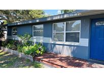 Charming home featuring a well-manicured front yard and inviting blue exterior with a quaint front porch at 1631 St Mary Dr, Dunedin, FL 34698