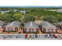Aerial view of apartment complex with lush greenery, lake views, and ample parking at 21032 Voyager Blvd # 8, Land O Lakes, FL 34638