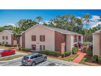 Exterior view of an apartment with red brick accents, well-maintained landscaping, and parking area at 21032 Voyager Blvd # 8, Land O Lakes, FL 34638
