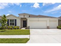 Charming single-story home featuring a three-car garage, well-manicured lawn, and appealing architectural details at 33700 Hamilton Hill Ln, Wesley Chapel, FL 33545