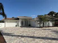 Beautiful single-story home with a red tile roof, white exterior, and lush landscaping with a paved driveway at 3691 Center Cir, Largo, FL 33774