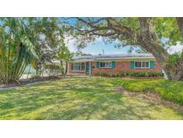 Charming brick home featuring well-maintained lawn, mature trees, and bright, eye-catching shutters at 4915 Chariton Ave, Tampa, FL 33603