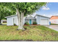 Charming single Gathering home featuring a vibrant blue front door, attached garage, and mature landscaping at 10110 Pepperidge Ct, Tampa, FL 33615