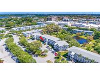 An aerial view of a condo building with well-manicured grounds and a pond, surrounded by trees and other buildings at 11224 82Nd Ave # 104, Seminole, FL 33772