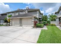 Exterior view of the townhome with a two-car garage and a well-maintained lawn at 14116 Trouville Dr, Tampa, FL 33624