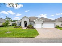 Charming single-story home with a well-manicured lawn and a brick driveway leading to a two-car garage at 19819 Tattnall Way, Brooksville, FL 34601