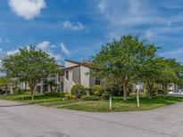 Inviting condo exterior featuring lush landscaping, mature trees, and ample parking at 2597 Countryside Blvd # 210, Clearwater, FL 33761