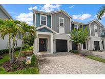Charming two-story townhome featuring a paver driveway, attached garage, and beautiful landscaping at 2816 Grand Kemerton Pl, Tampa, FL 33618