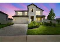 Charming two-story home with a stone facade, two-car garage, and professionally landscaped front yard at 33287 Sycamore Leaf Dr, Wesley Chapel, FL 33545