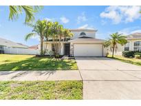 Charming two-story home with a well-manicured lawn, mature palms, and a two-car garage at 419 Stone Briar Dr, Ruskin, FL 33570