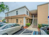 Two-story condo building with tan stucco and white siding, featuring stairs to upper-level units and designated parking at 4708 Michael Ct # 103, Tampa, FL 33614
