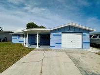 Charming blue one-story home featuring a front-facing garage, covered porch, and well-maintained yard at 4836 Daphne St, New Port Richey, FL 34652