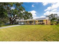 Charming single-story home with a lush green lawn, covered front porch, and carport with solar panels at 5675 Lown N St, St Petersburg, FL 33714