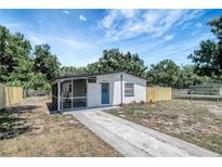 Charming single-story home with a blue door, screened porch, fresh paint, and a well-maintained front yard at 6014 S 82Nd St, Tampa, FL 33619