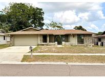 Charming single-story home featuring stone accents, a two-car garage, and a well-maintained front yard at 613 Sandy Hollow Rd, Tarpon Springs, FL 34689