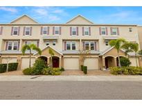 Attractive exterior townhome row with neutral paint, purple shutters, paved driveways and lush landscaping at 807 Callista Cay Loop, Tarpon Springs, FL 34689
