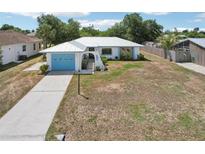 Charming single-story home with a blue garage door, decorative seahorse accent, and a well-maintained lawn at 953 Tropical Nw Ave, Port Charlotte, FL 33948