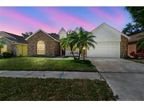 Charming single-Gathering home with a brick facade, two-car garage, well-manicured lawn, and palm tree at 9709 Bay Colony Dr, Riverview, FL 33578