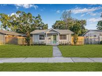 Charming single-story home with a well-manicured lawn, mature trees and a tidy walkway to the front door at 1052 55Th N Ave, St Petersburg, FL 33703