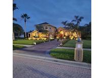 Stunning home at dusk featuring lush landscaping, elegant lighting, and a paver driveway at 10532 Cory Lake Dr, Tampa, FL 33647