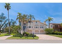 Beautiful, two-story home with lush tropical landscaping, a brick driveway and an attached three-car garage at 1156 2Nd S Ave, Tierra Verde, FL 33715