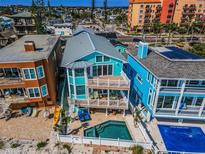 Stunning three-story beachfront home with balconies, a pool, and coastal charm at 13303 Gulf Ln, Madeira Beach, FL 33708