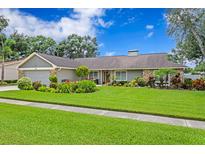 Charming single-story home features beautiful landscaping, a well-maintained lawn, and stone accents at 13810 Lake Village Pl, Tampa, FL 33618