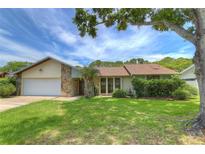 Charming single-Gathering home featuring a stone facade, attached garage and mature landscaping at 313 Oak Crest Dr, Safety Harbor, FL 34695