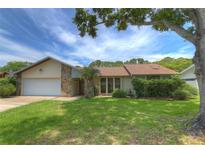 Charming single-story home featuring a well-manicured lawn and a stone facade accent, offering a welcoming curb appeal at 313 Oak Crest Dr, Safety Harbor, FL 34695
