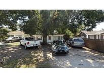 Modest single-story home with mature trees and gravel yard featuring various vehicles parked on the property at 3424 16Th E St, Bradenton, FL 34208
