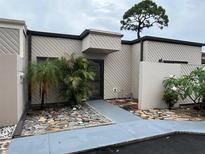 Charming townhome featuring a unique tree overhanging, stone walkway, and neutral paint scheme at 4309 Cedar Grove St, Holiday, FL 34691