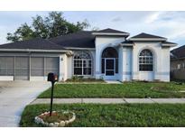 Charming single-story home with an attached garage, arched windows, and well-manicured lawn at 6213 Ashfield Pl, Wesley Chapel, FL 33545