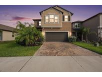 Charming two-story home featuring manicured landscaping, a brick driveway, and a two-car garage at 8719 Winning Fields Rd, New Port Richey, FL 34655