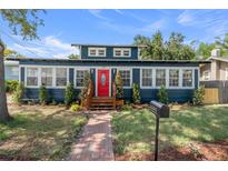 Charming single-story home featuring a red front door, brick pathway, and well-manicured landscaping at 100 E Fern St, Tampa, FL 33604