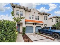 Charming two-story home showcasing blue garages and a terracotta tile roof with lush landscaping at 102 S Moody Ave # 1, Tampa, FL 33609