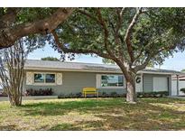 Charming single-story home with mature trees, green lawn, and a cheerful yellow bench out front at 11720 80Th Ave, Seminole, FL 33772