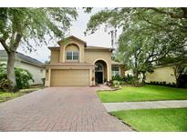 Charming two-story home featuring a brick driveway, attached two car garage, and landscaped front yard at 11821 Easthampton Dr, Tampa, FL 33626