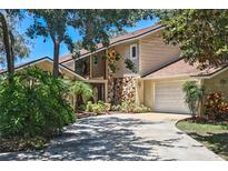 Charming two-story home with a stone chimney and attached two-car garage, surrounded by mature landscaping at 12929 Sugar Creek Blvd, Hudson, FL 34669