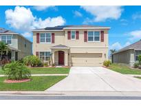 Two-story home with a two-car garage, solar panels, and well-manicured landscaping at 14135 Arbor Pines Dr, Riverview, FL 33579